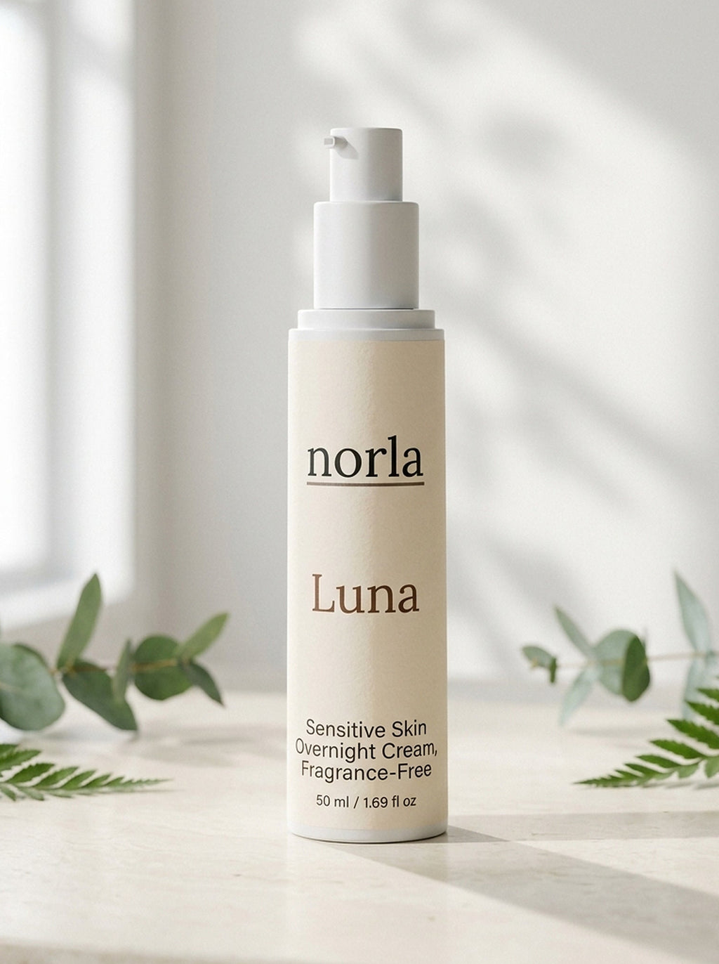 Luna Sensitive Skin Overnight Cream 50 ml by Norla, airless pump bottle on a marble surface with eucalyptus and fern